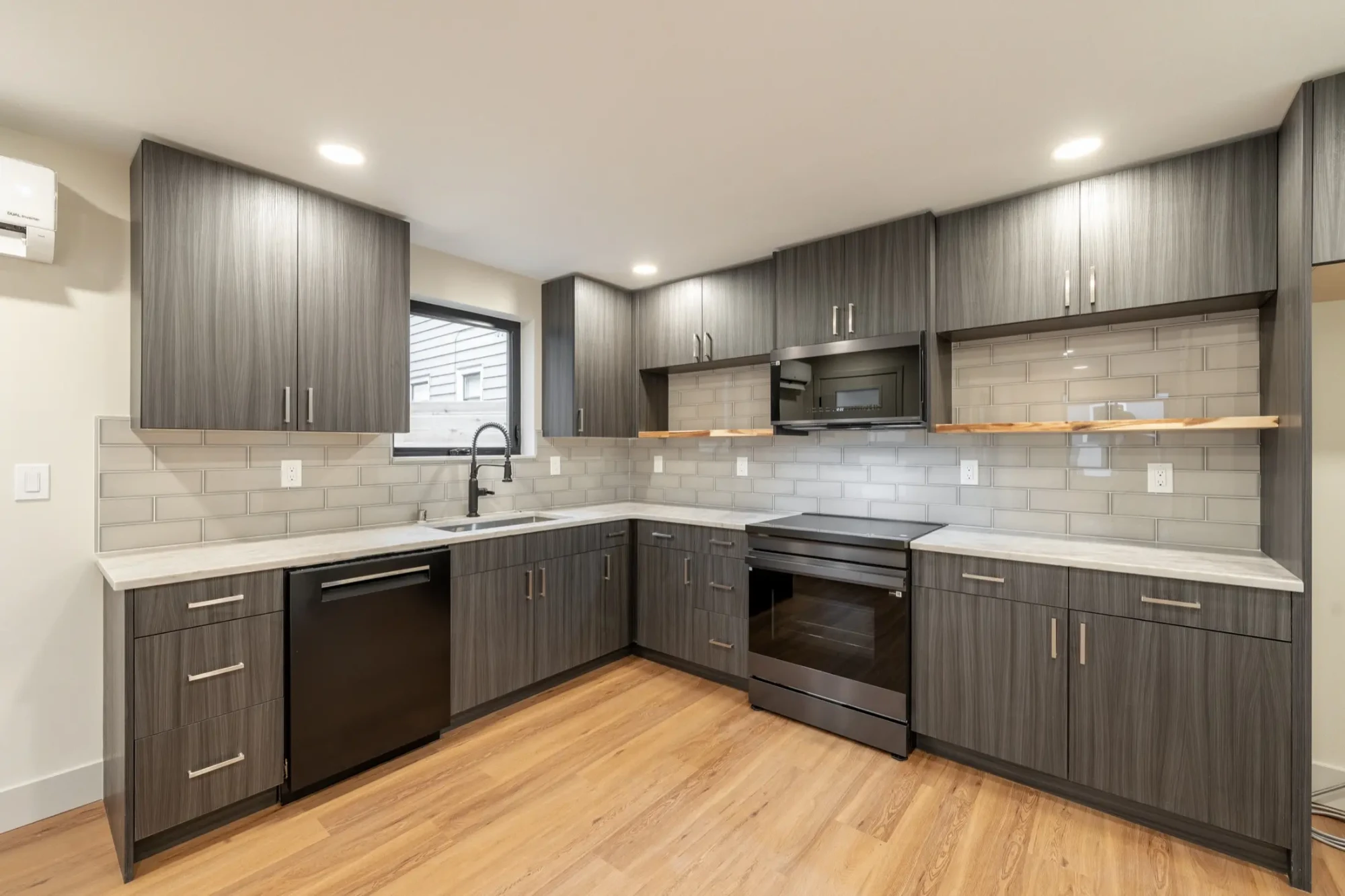 A finished DIGS kitchen — grey cabinetry, quartz counters and wide-plank floors